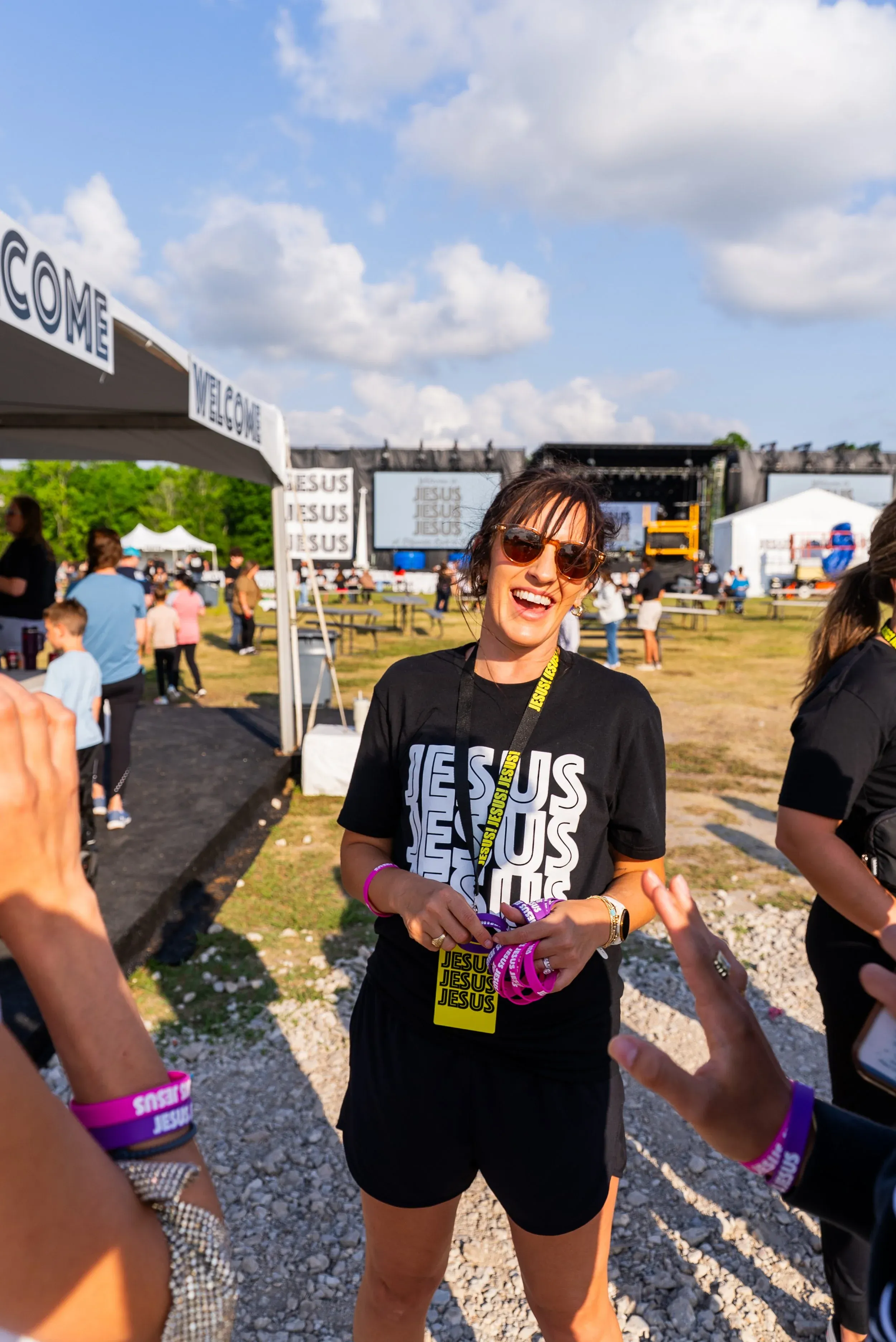 A woman in a JESUS, JESUS, JESUS shirt smiling at golden hour