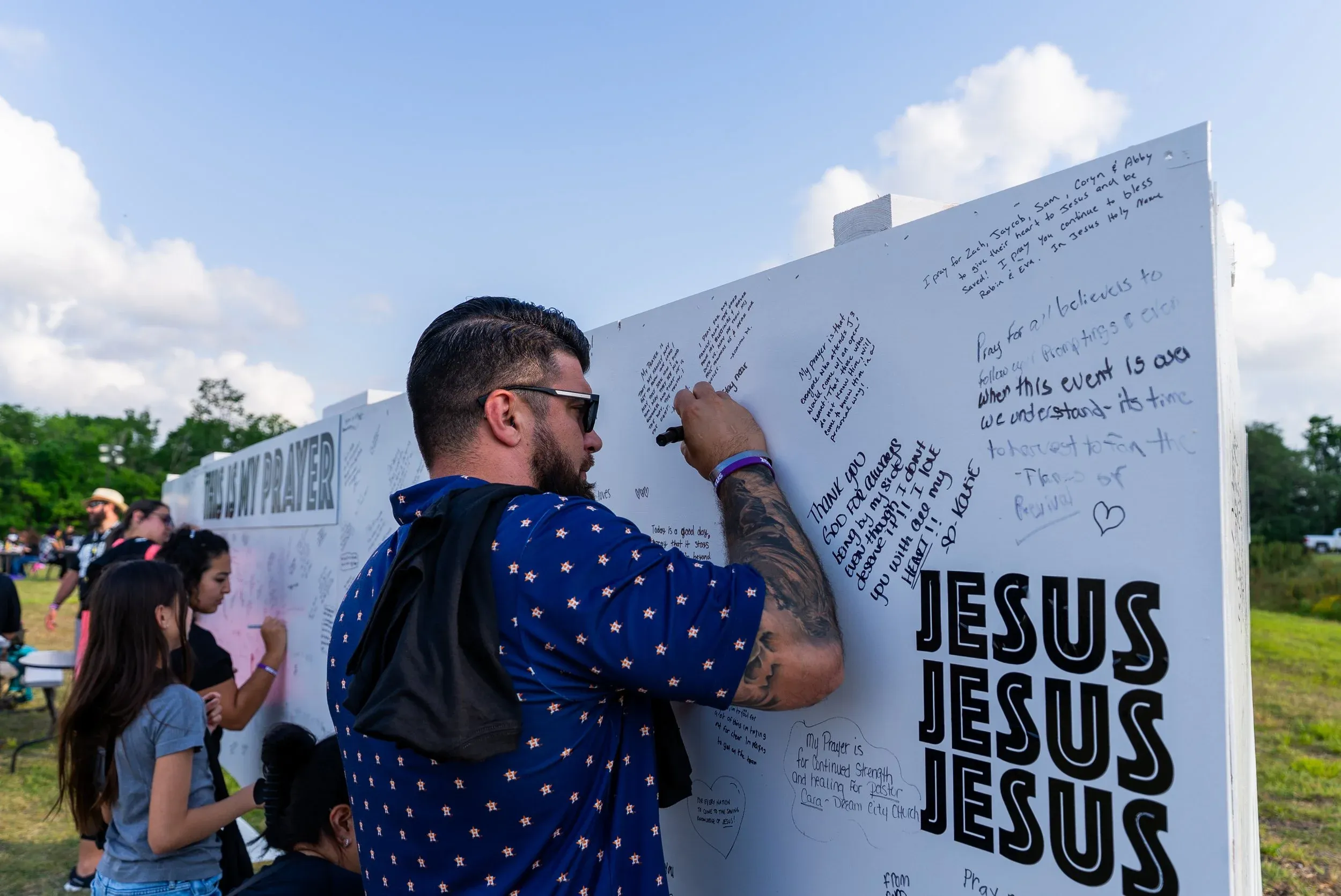 A man writing a prayer on the JESUS, JESUS, JESUS prayer wall