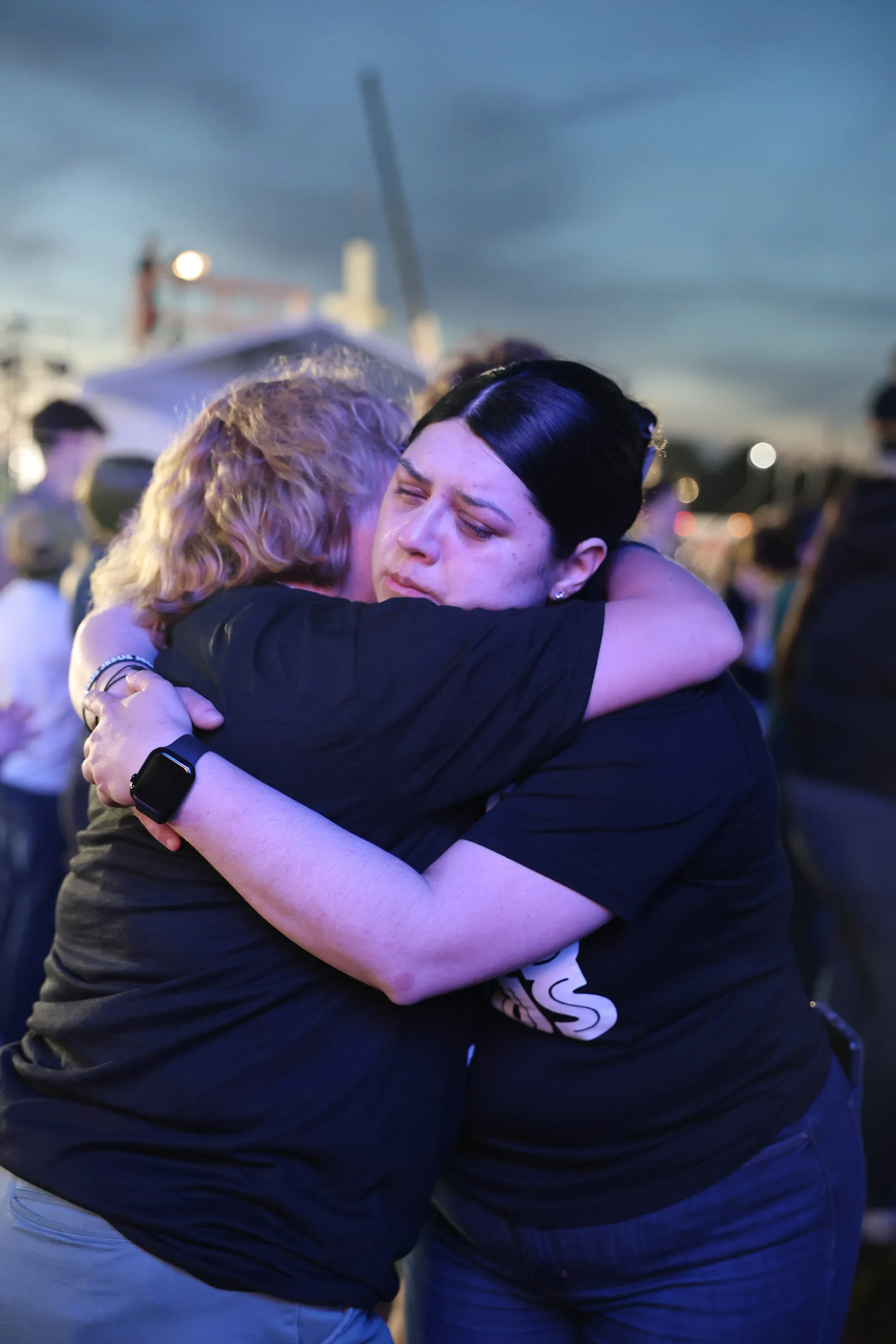 Two women embracing in prayer at night